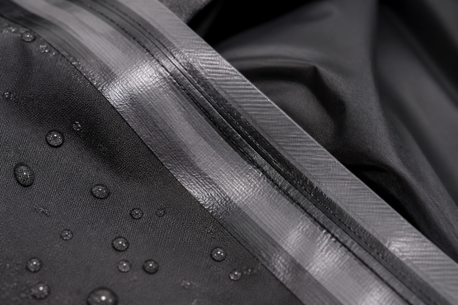 Close-up of waterproof seam tape on motorcycle rain jacket showing quality construction with macro photography